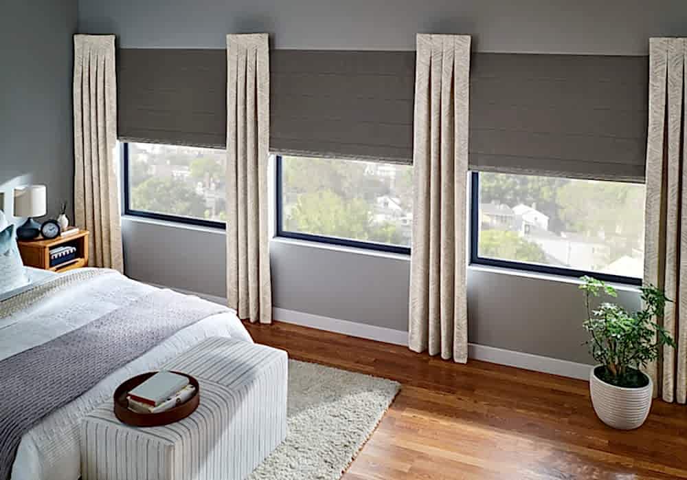 Roman shades filtering in light into a bedroom.
